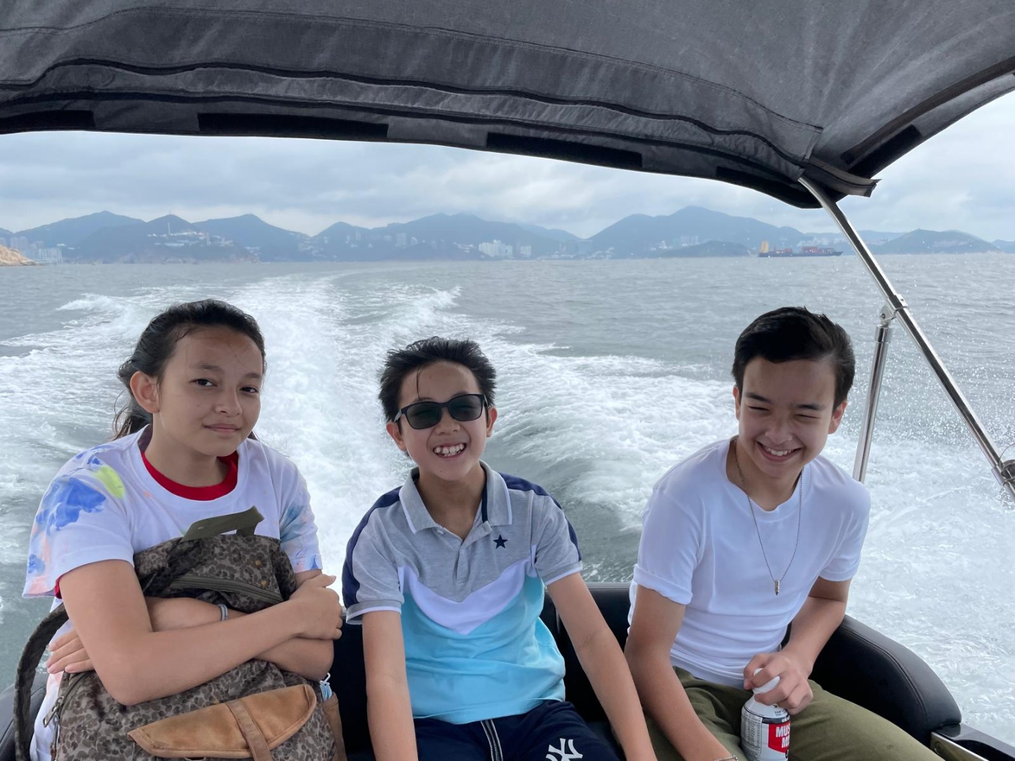 Three young volunteers on a tender boat heading to a remote beach